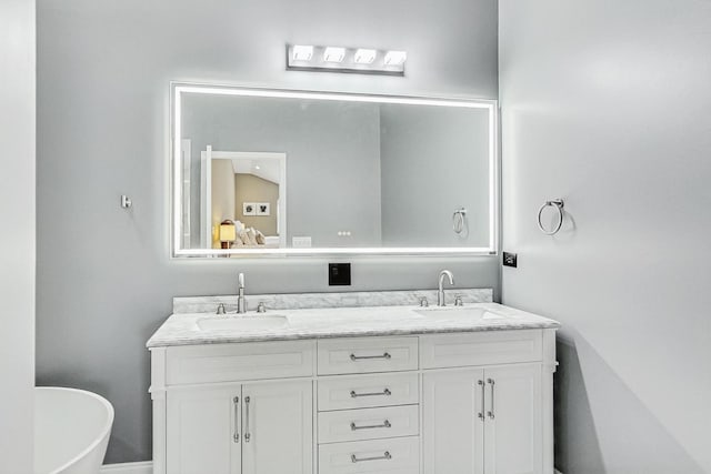 bathroom featuring a freestanding bath, double vanity, and a sink