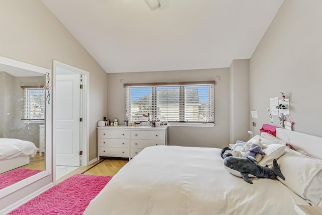 bedroom with light wood-type flooring and vaulted ceiling