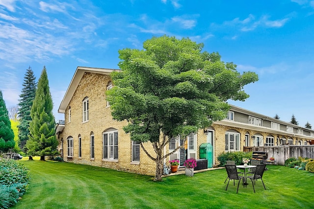 back of property featuring a yard, brick siding, and fence