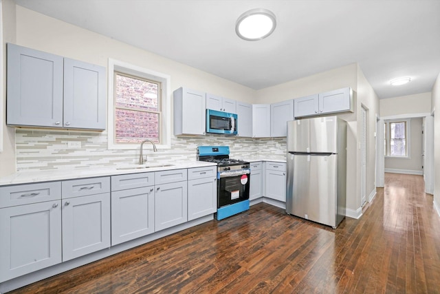 kitchen with sink, stainless steel appliances, gray cabinetry, and backsplash