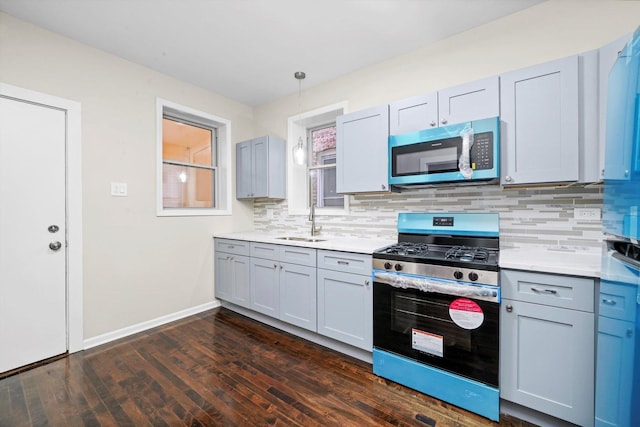 kitchen featuring dark hardwood / wood-style flooring, sink, tasteful backsplash, stainless steel gas range oven, and pendant lighting