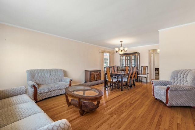 living area with light wood-type flooring, a notable chandelier, and crown molding