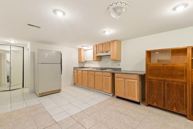 kitchen with white appliances, visible vents, light tile patterned flooring, a sink, and under cabinet range hood