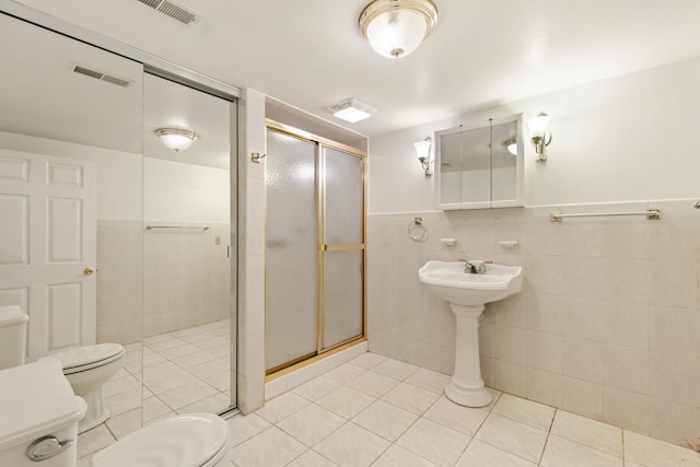 full bathroom with tile patterned floors, visible vents, toilet, a stall shower, and tile walls