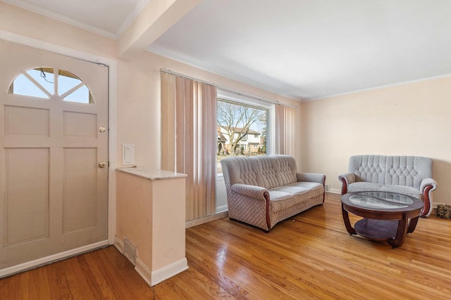 foyer entrance with light wood-style flooring, crown molding, and baseboards