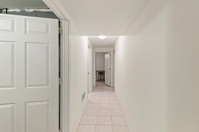 hallway with light tile patterned floors, visible vents, and baseboards