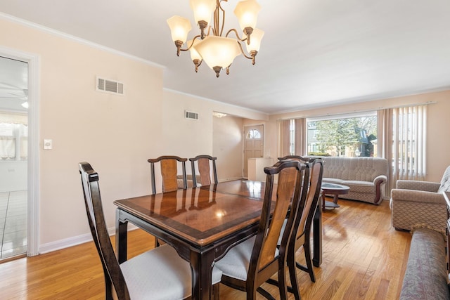 dining space featuring visible vents, baseboards, light wood-style flooring, and ornamental molding