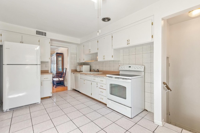 kitchen with visible vents, light countertops, light tile patterned flooring, white appliances, and a sink