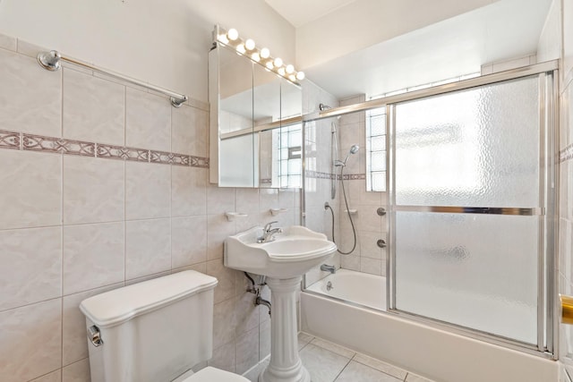 full bath featuring tile patterned flooring, toilet, tile walls, and bath / shower combo with glass door