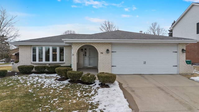 ranch-style home featuring an attached garage, roof with shingles, concrete driveway, and brick siding