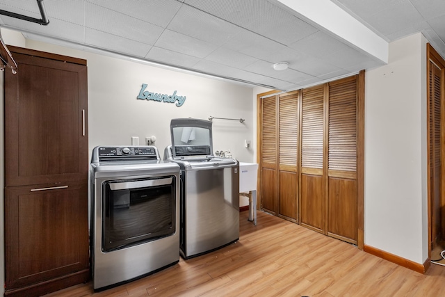 laundry room with light wood-type flooring, baseboards, and separate washer and dryer