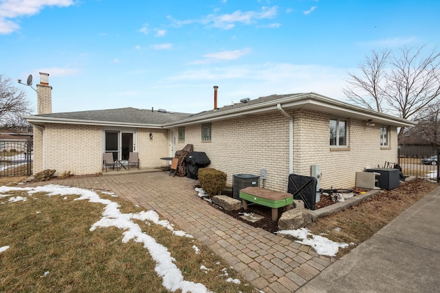 back of house with brick siding, a chimney, a patio area, and fence