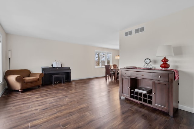 living area with dark wood-type flooring, visible vents, and baseboards