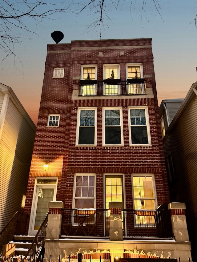 exterior space featuring stairs, brick siding, and a balcony