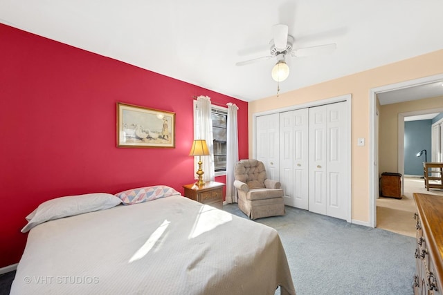 carpeted bedroom featuring an accent wall, a ceiling fan, a closet, and baseboards