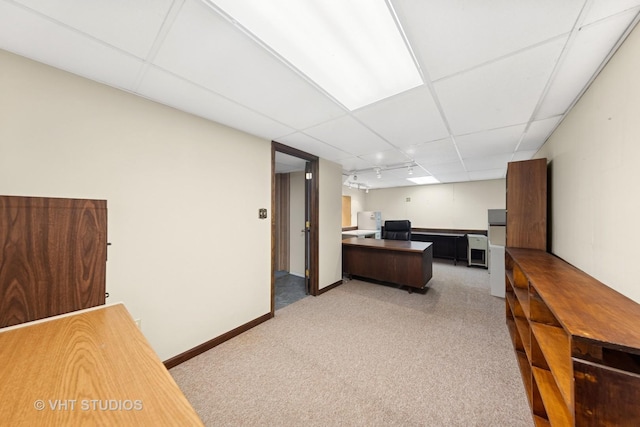 office space featuring a drop ceiling, light colored carpet, and baseboards