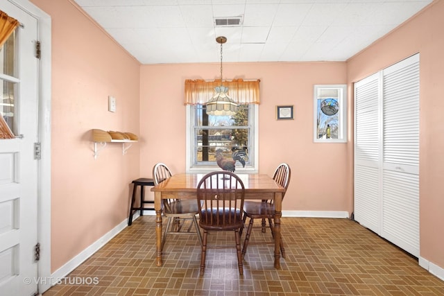 dining space with baseboards, visible vents, and brick patterned floor