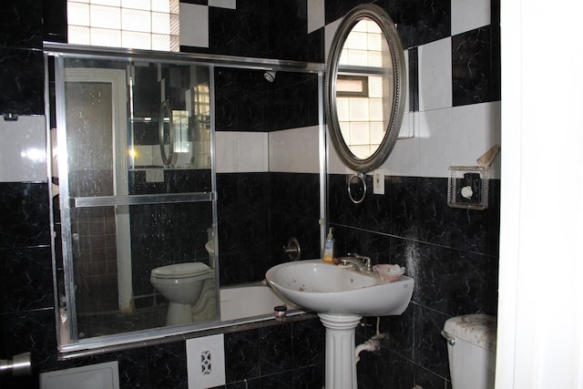 bathroom featuring a tub, tile walls, and toilet