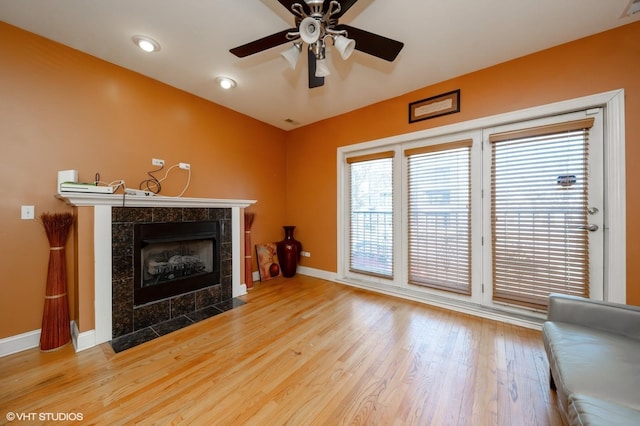 living room with a fireplace, ceiling fan, and light hardwood / wood-style floors