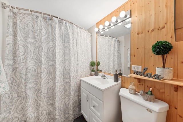 bathroom featuring vanity, toilet, and wood walls