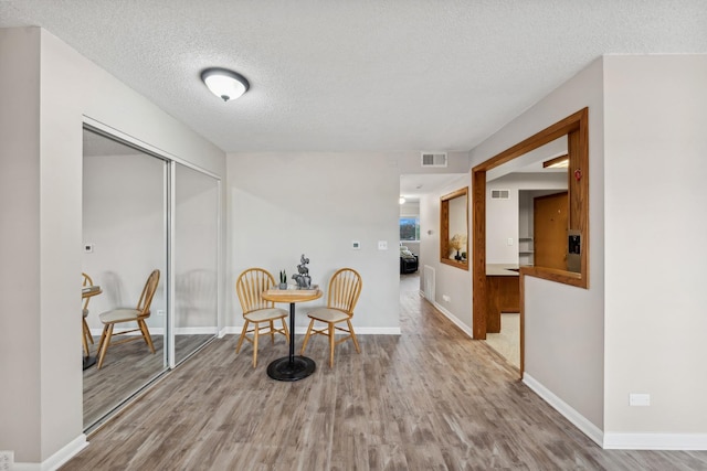 living area featuring a textured ceiling and light hardwood / wood-style flooring