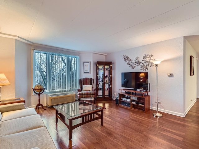 living area featuring an AC wall unit, baseboards, and wood finished floors