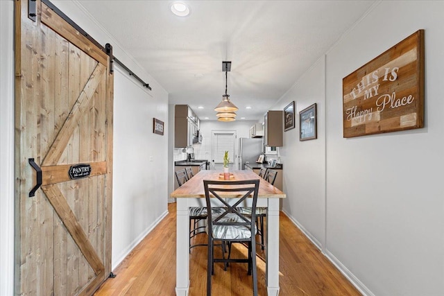 dining room featuring recessed lighting, baseboards, light wood finished floors, and a barn door