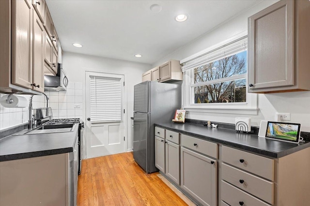 kitchen with stainless steel appliances, dark countertops, gray cabinets, and light wood-style floors