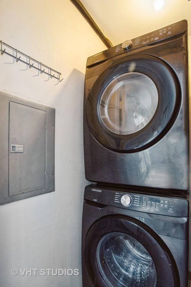 washroom featuring stacked washer and dryer, laundry area, and electric panel