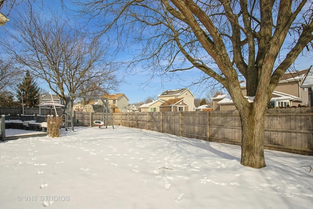 yard covered in snow featuring a residential view and fence