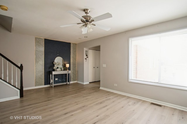 spare room featuring wood finished floors, visible vents, baseboards, and stairs