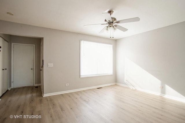 spare room featuring a ceiling fan, light wood-type flooring, and baseboards