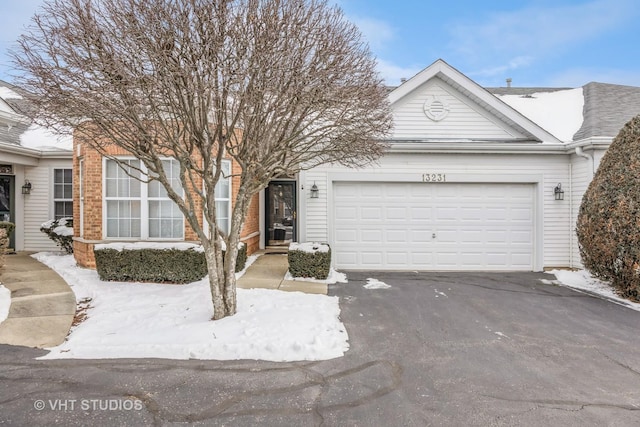 view of front of home with an attached garage, driveway, and brick siding