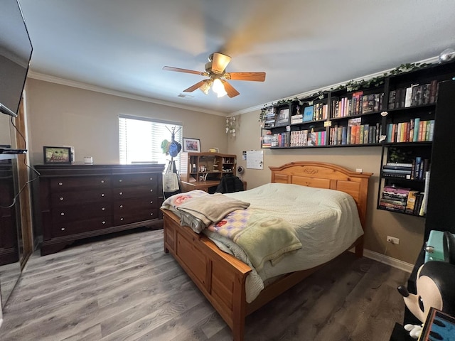 bedroom featuring hardwood / wood-style flooring, ornamental molding, and ceiling fan