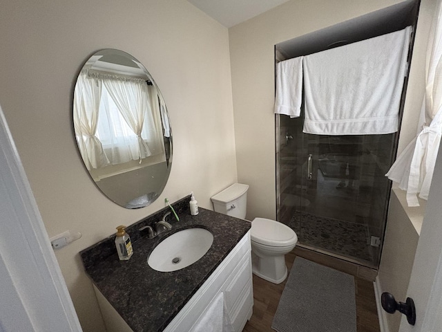 bathroom with hardwood / wood-style flooring, walk in shower, vanity, and toilet