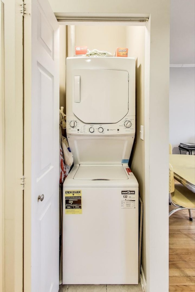 clothes washing area with light wood-style floors, stacked washer / drying machine, and laundry area