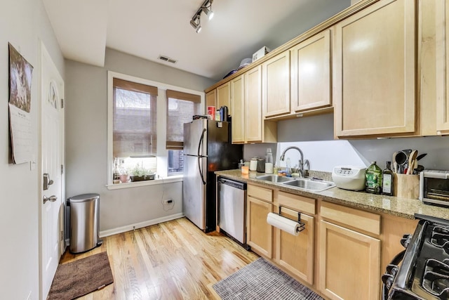 kitchen with a sink, visible vents, light wood-style floors, appliances with stainless steel finishes, and light brown cabinetry