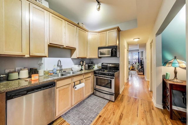 kitchen with light wood finished floors, rail lighting, appliances with stainless steel finishes, light brown cabinets, and a sink