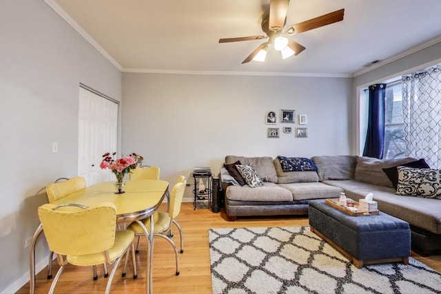 living area with ornamental molding, a ceiling fan, baseboards, and wood finished floors