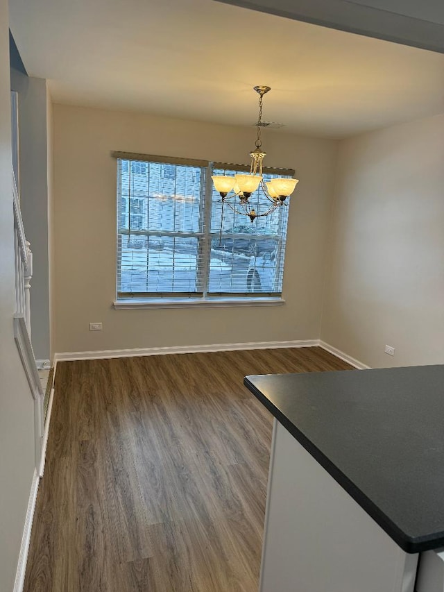 unfurnished dining area featuring an inviting chandelier and dark hardwood / wood-style floors