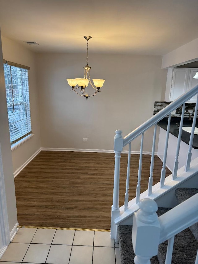 staircase with a notable chandelier and tile patterned floors