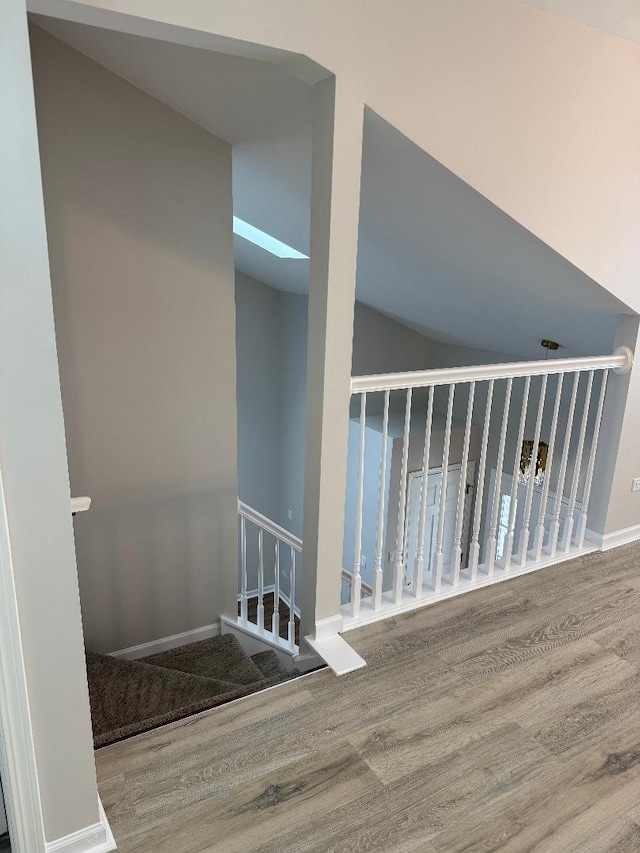 staircase featuring vaulted ceiling with skylight and hardwood / wood-style floors