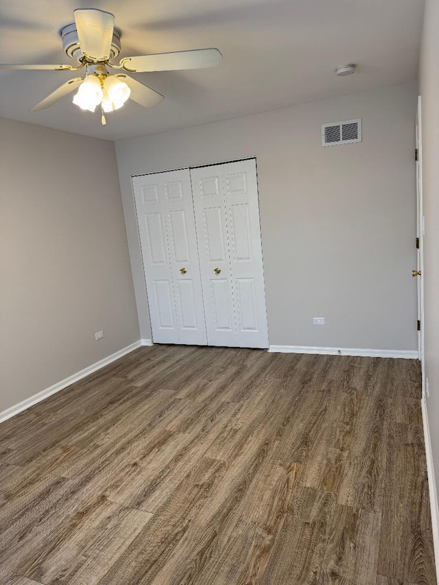 unfurnished bedroom with ceiling fan, dark hardwood / wood-style flooring, and a closet