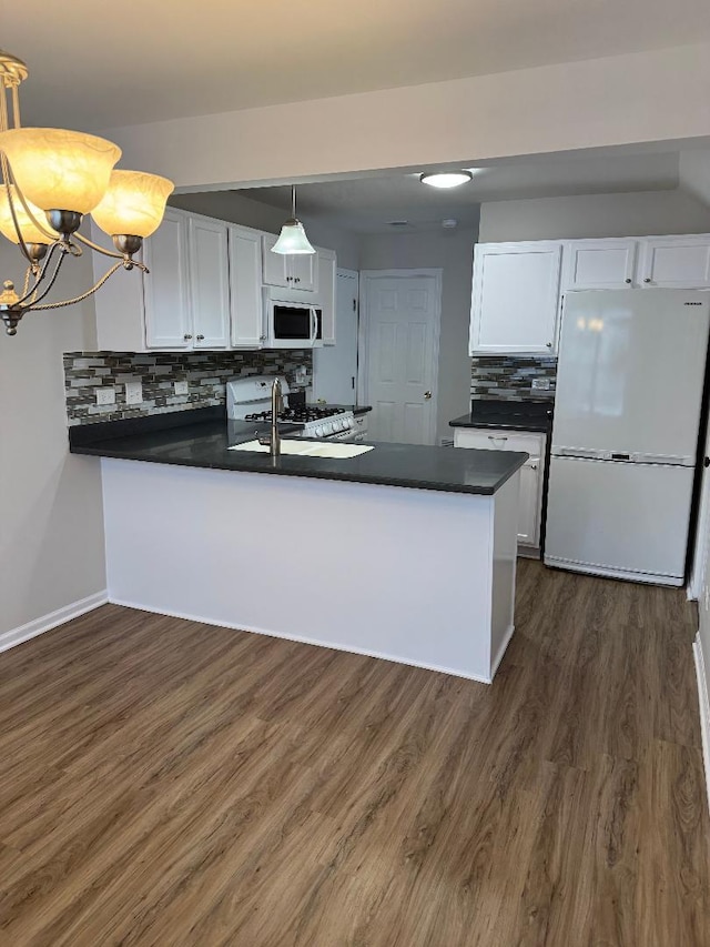 kitchen featuring white appliances, decorative light fixtures, kitchen peninsula, and white cabinets