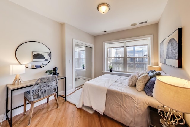 bedroom featuring light wood-style flooring, a closet, visible vents, and baseboards