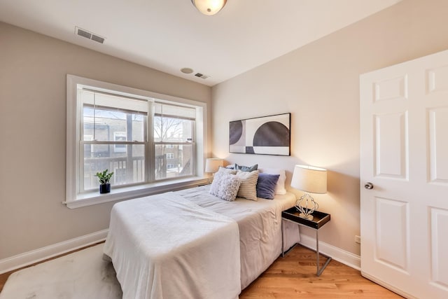 bedroom with visible vents, light wood finished floors, and baseboards