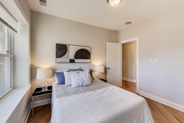 bedroom featuring visible vents, baseboards, and wood finished floors