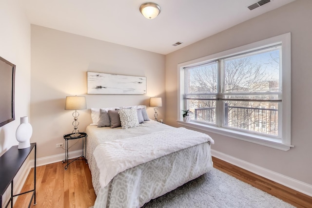 bedroom with wood finished floors, visible vents, and baseboards