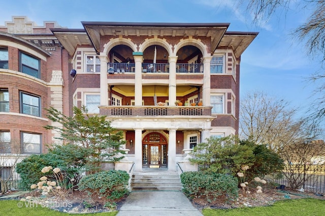 view of front of property featuring a balcony and brick siding