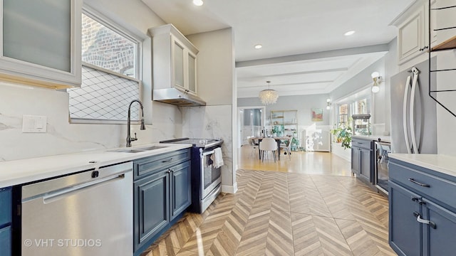 kitchen featuring light countertops, backsplash, appliances with stainless steel finishes, a sink, and blue cabinets